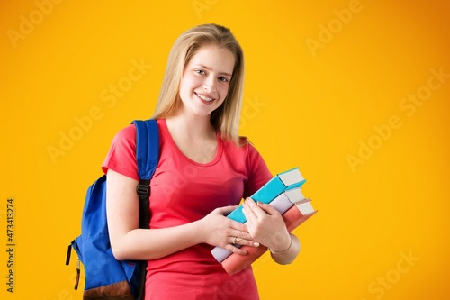 Smiling woman student with school books in hands on the background.