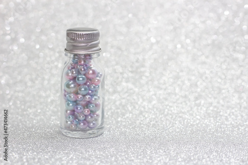 Bottle full of pearls on glitter background