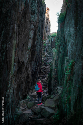 Woman hiking through Kungsklyftan canyon with mossy rocks by village Fjällbacka in Sweden.