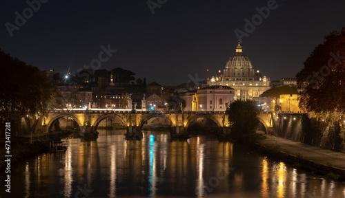 View of the St. Peter's basilica dome with the Vittorio Emanuele II bridge at the foreground, Vatican City, Rome. Light reflection in the water of the Tiber river in the late evening. © A.Pushkin