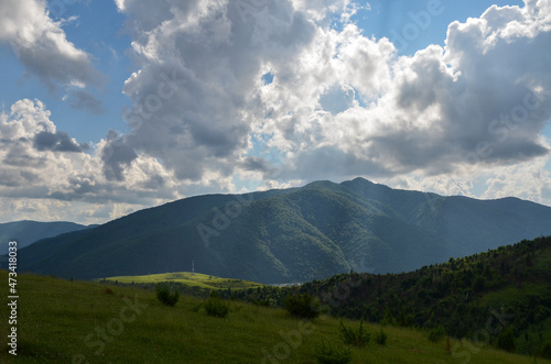 Picturesque landscape with green meadows and forest on hills and mountains at the distance. Carpathian countryside view in summer