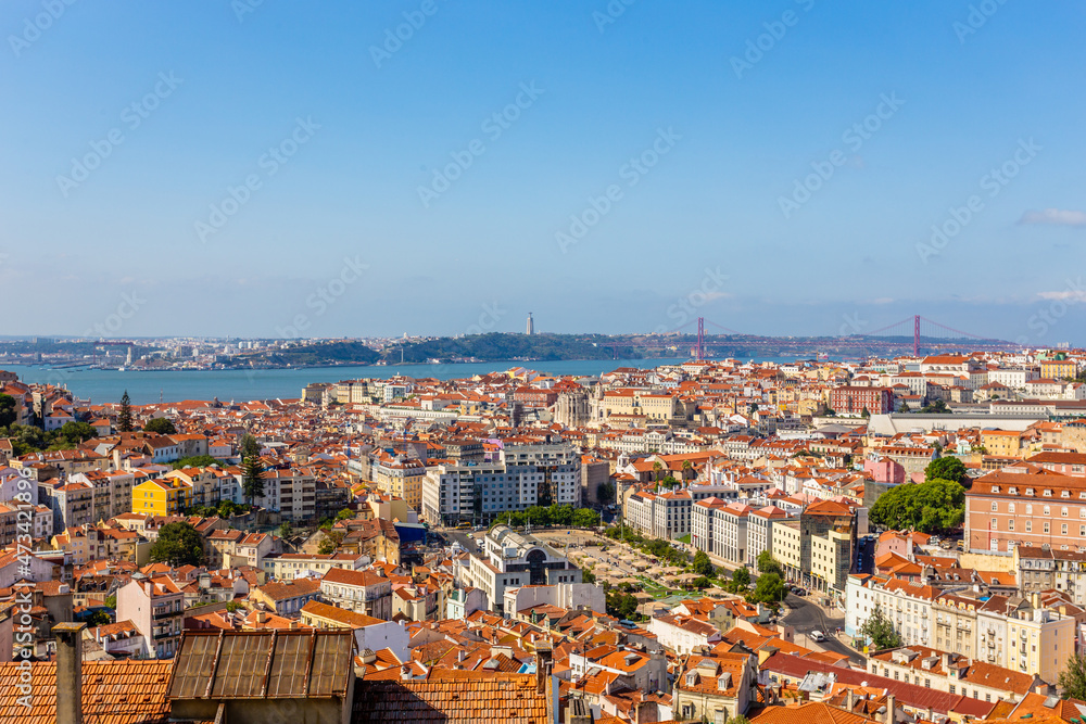 View to downtown of Lisbon with miltiple streets and houses and bridge of 25 of April over Tagys river, Portugal