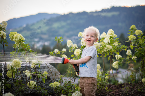 A boy laughing and watering flowers photo
