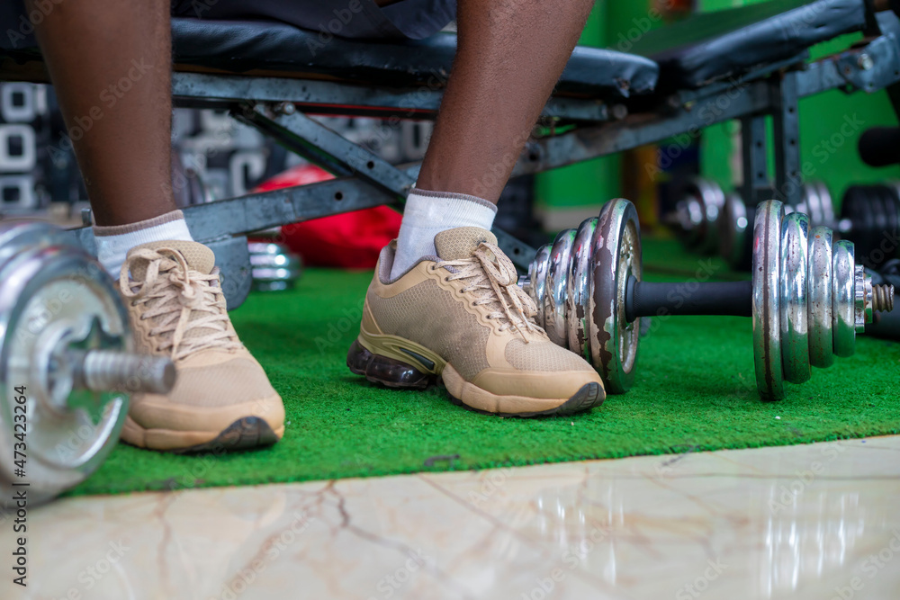 Morning workout routine in home gym. Fitness motivation and muscle training concept. Man in sneakers tying shoelaces. Athlete starting exercise with dumbbell weight. Morning workout routine in home gym. Fitness motivation and muscle training concept. Man in sneakers tying shoelaces. Athlete starting exercise with dumbbell weight.