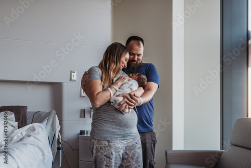Newborn baby boy being cradled by new parents in birthing center