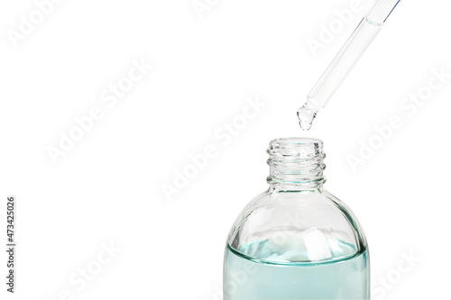 Pipette with oil drop into glass bottle on white background. photo