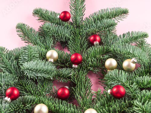 Christmas tree spruce branch decorated with red baubles on pink
