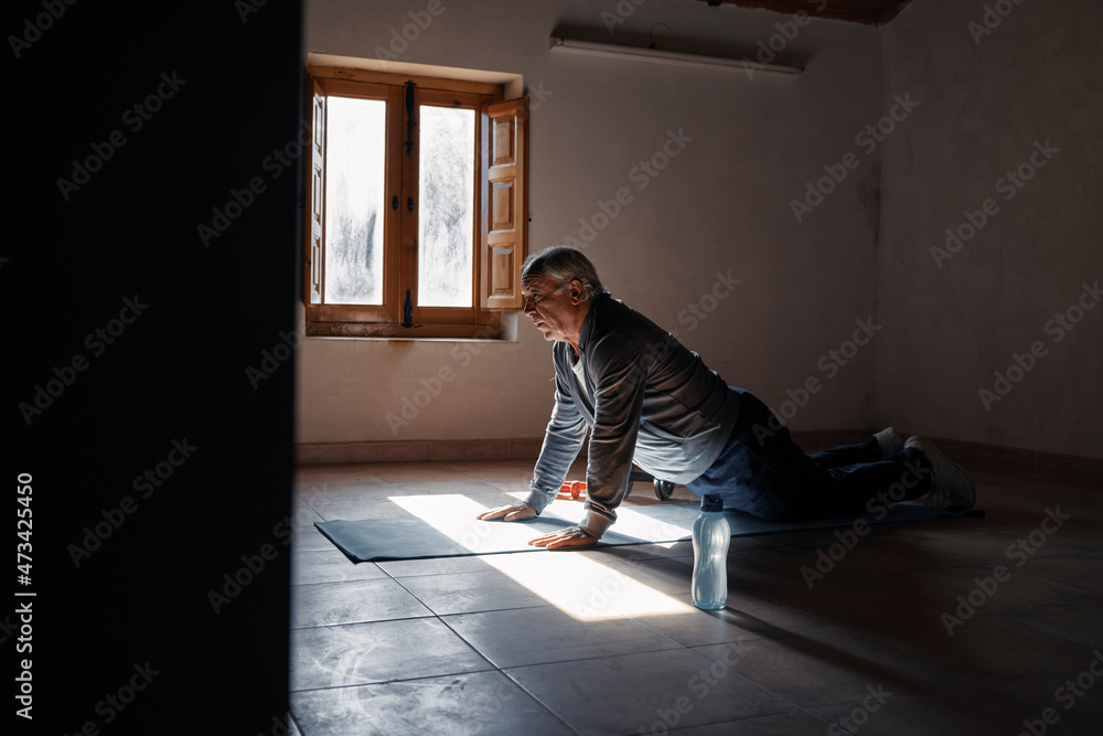 An elderly man doing push-ups at home An elderly man doing push-ups at home