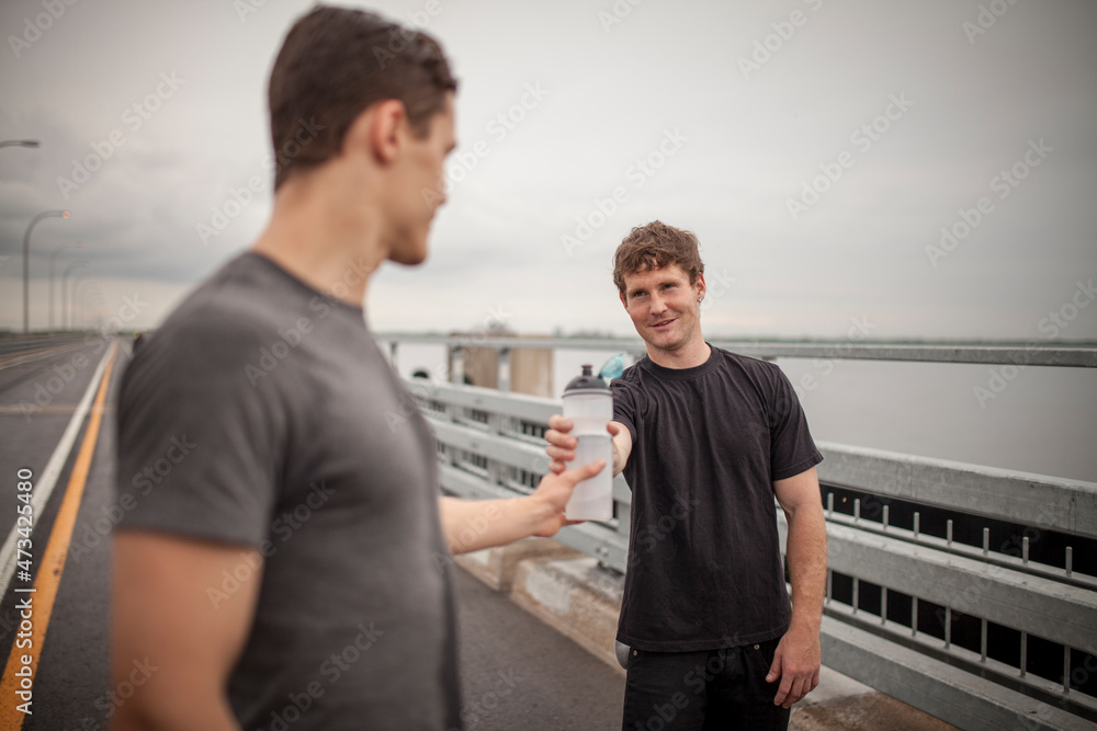 Male athletes sharing water trying to rehydrate during workout o Male athletes sharing water trying to rehydrate during workout o