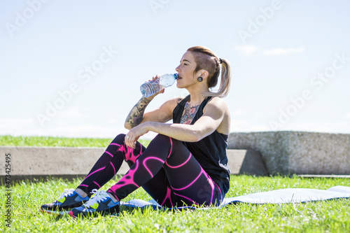 Young female athlete resting and drinking during a water break photo