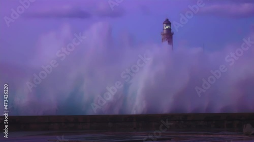 wave crashing on malecon with the Faro Castillo del Morro lighthouse. Havana, Cuba photo