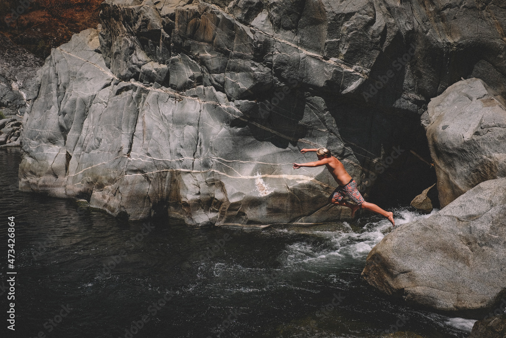 Boy Leaps into Swimming Hole Flowing Water and Granite Canyon Walll Boy Leaps into Swimming Hole Flowing Water and Granite Canyon Walll