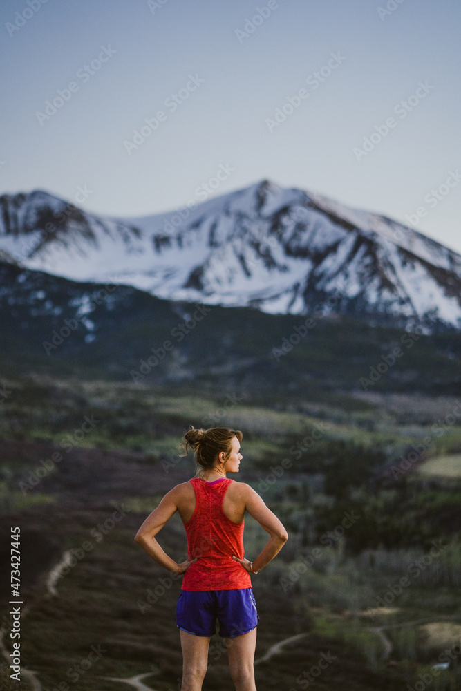 Young woman looks out at the mountains while trail running at dawn Young woman looks out at the mountains while trail running at dawn