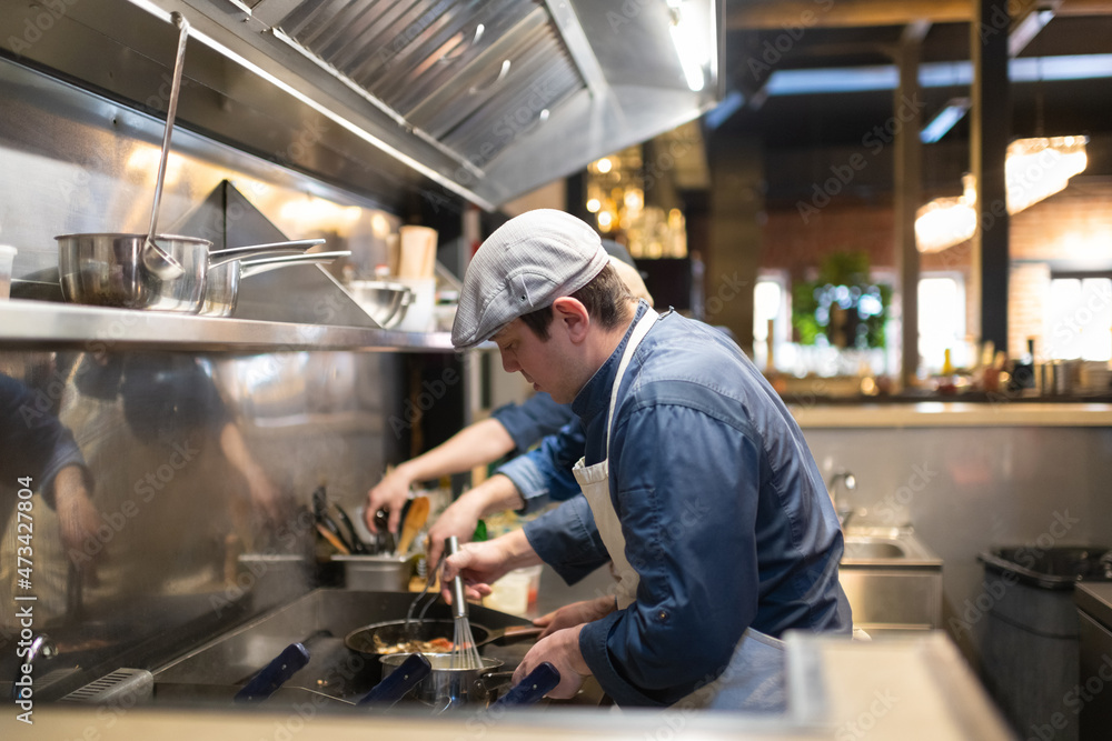 Man cooking sauce in restaurant kitchen Man cooking sauce in restaurant kitchen