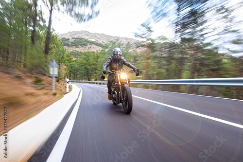 Rider with black cuscom motorcycle in the road at sunset