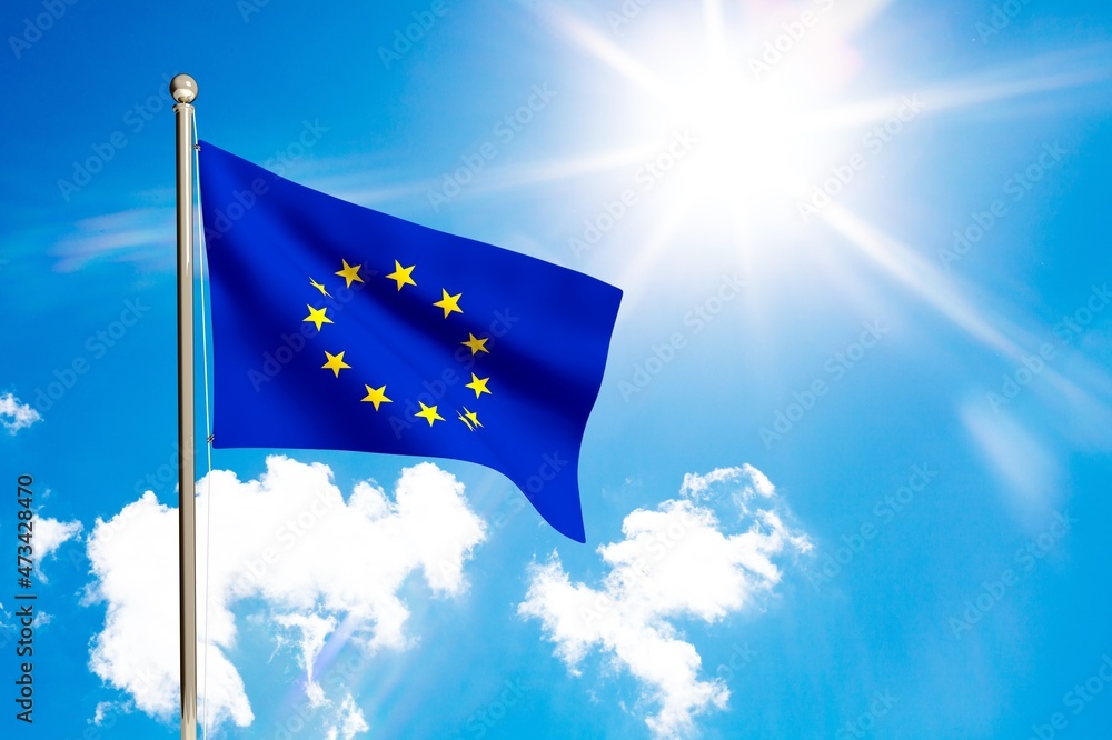 National Europe flag waving in the wind, against the blue sky with sunbeams.