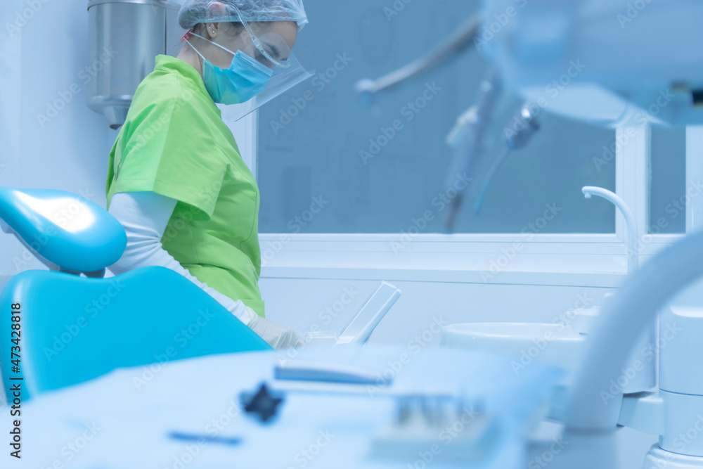 Woman dentist with face mask and face shield, dental clinic Woman dentist with face mask and face shield, dental clinic