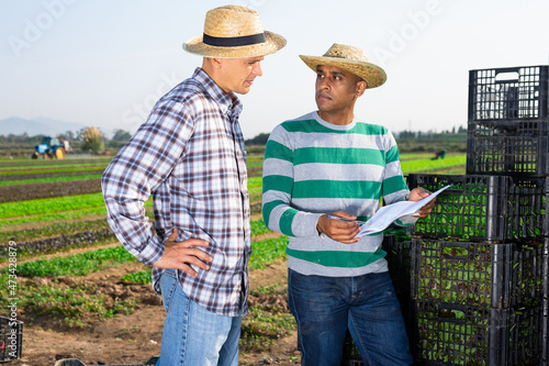 Two males farm workers talking and signing documents outdoors