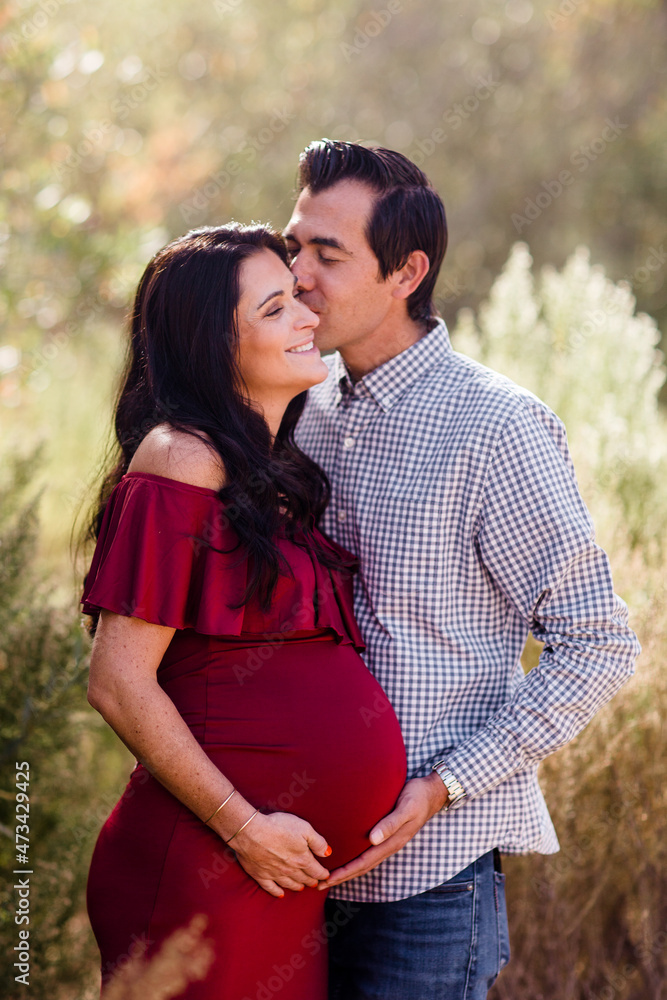 Husband Kissing Expectant Wife in Field in San Diego Husband Kissing Expectant Wife in Field in San Diego