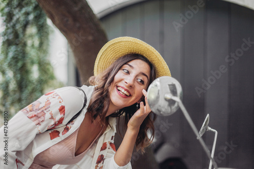Woman in straw hat looking a bike's mirror and smiling