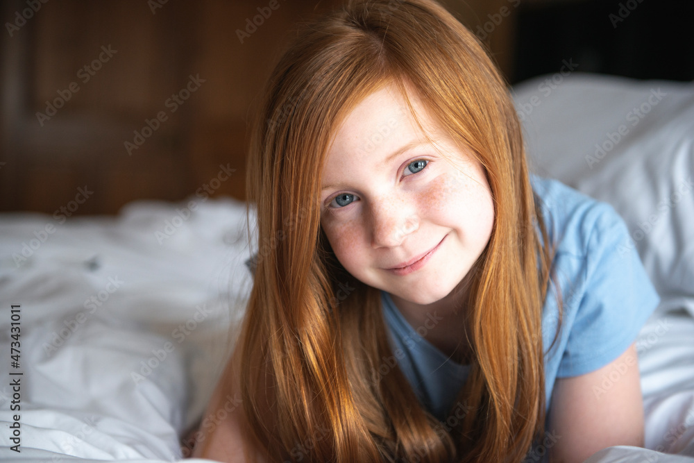 Young happy red haired blue eyed girl laying on white bed. Young happy red haired blue eyed girl laying on white bed.