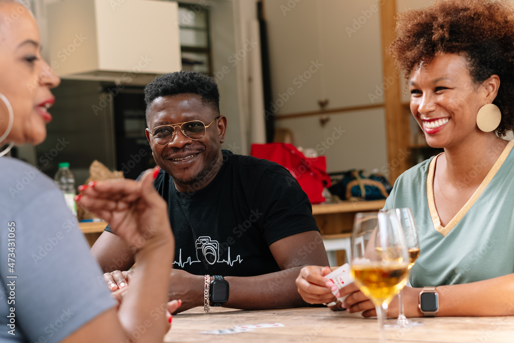 Friends playing cards while enjoying wine at home Friends playing cards while enjoying wine at home