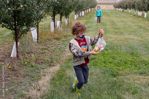 Siblings picking apples on a fall day in an orchard in Illinois photo