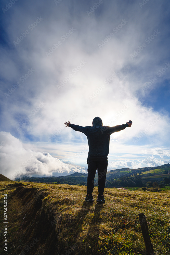 Unrecognizable man on top of the mountain with his arms open looks at the majesty of the landscape Unrecognizable man on top of the mountain with his arms open looks at the majesty of the landscape