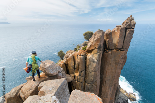 Female adventurer heads off into the unkown, armed with ropes and climbing gear, as she explores dolerite rock columns in the  sea cliffs of Cape Raoul, in Tasmania, Australia. photo