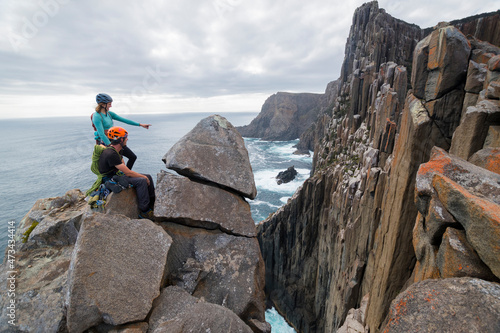 A male and a female rockclimber point at the next challenge they will tackle, scoping out possible ways up the sea cliffs of Cape Raoul, Tasmania, Australia. photo