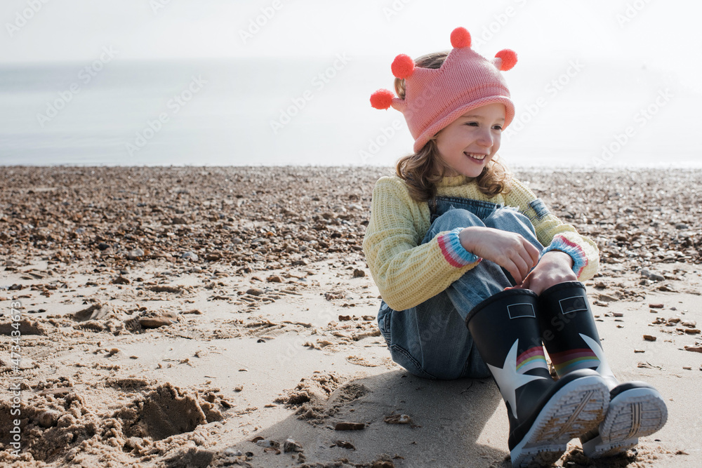 girl sat smiling on the beach wearing a crown on a sunny day in the UK girl sat smiling on the beach wearing a crown on a sunny day in the UK