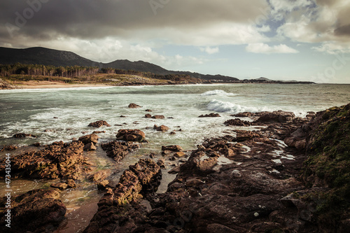 Rocky beach with waves and mountains in the background photo