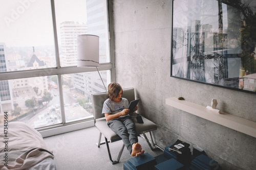 Boy Works on iPad from a hotel room in the City photo