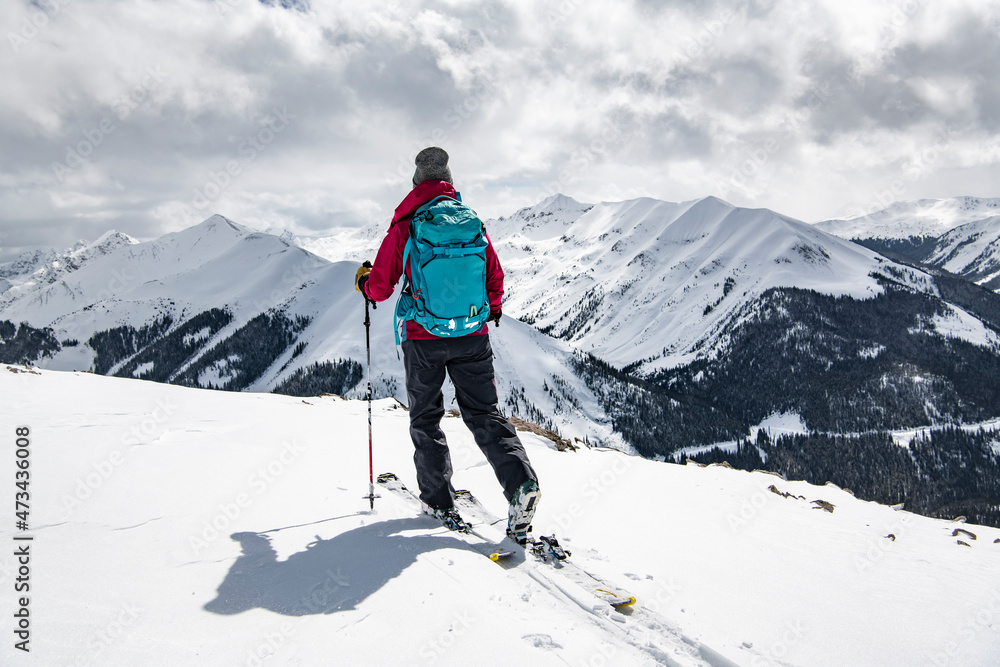 Rear view of woman with skis on snowcapped mountain against sky during vacation Rear view of woman with skis on snowcapped mountain against sky during vacation
