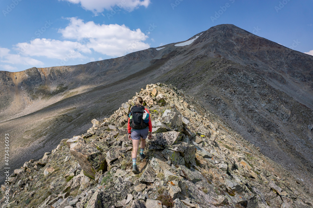 Rear view of female hiker walking on rocks at mountain Rear view of female hiker walking on rocks at mountain