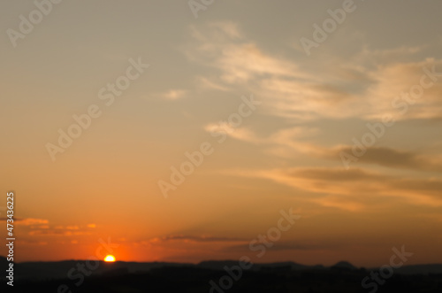 Sunset over a mountain, with the sun in the distance