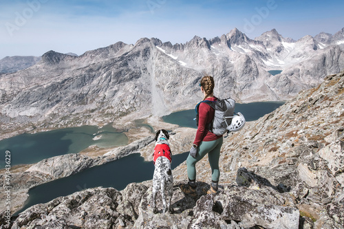 Young woman hiking with dog on mountain during vacation photo