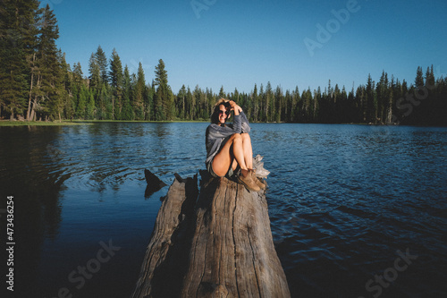 Blonde Woman Poses on a log over water at Sunset. photo