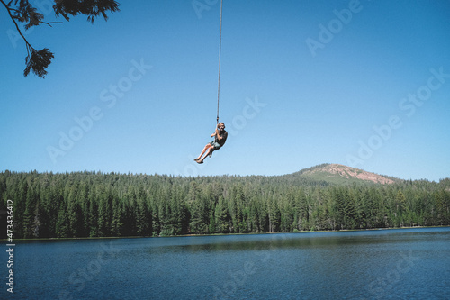 Young Boy Swings High above the lake on a rope swing photo