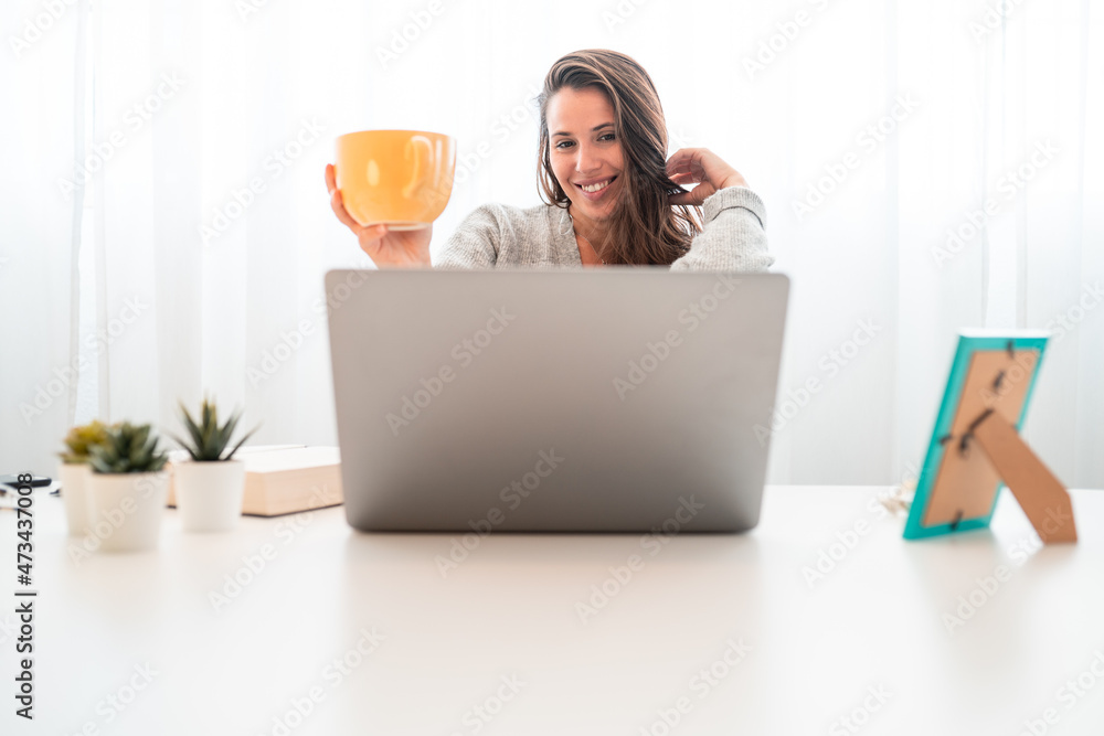 young woman working with computer at home while drinking a cup of coff young woman working with computer at home while drinking a cup of coff