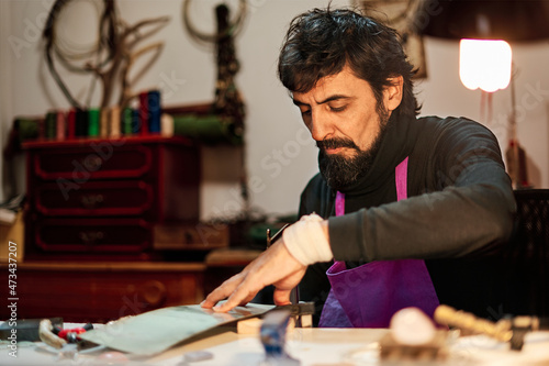 Craftsman cutting a metal plate with a saw at the work table