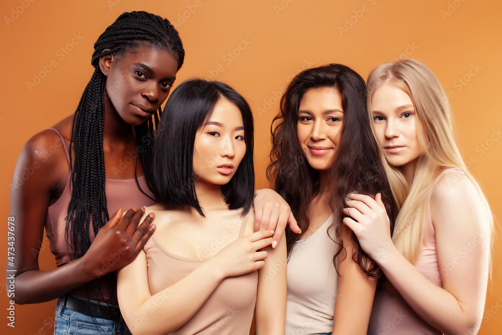 Obraz premium young pretty asian, caucasian, african woman posing cheerful together on brown background, lifestyle diverse nationality people concept