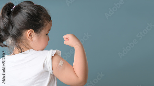 Little asian girl with bandage plaster on her arm after Covid-19 vaccination. Injection covid vaccine, healthcare for children
