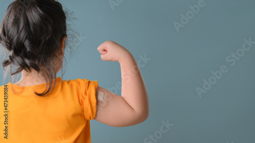 Little asian girl with bandage plaster on her arm after Covid-19 vaccination. Injection covid vaccine, healthcare for children