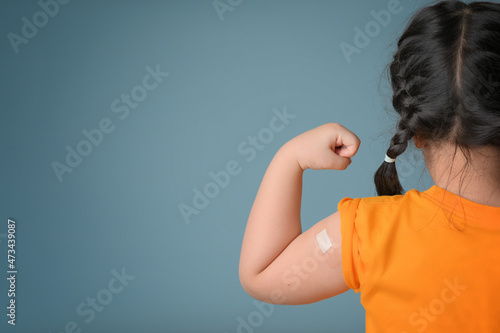 Little asian girl with bandage plaster on her arm after Covid-19 vaccination. Injection covid vaccine, healthcare for children