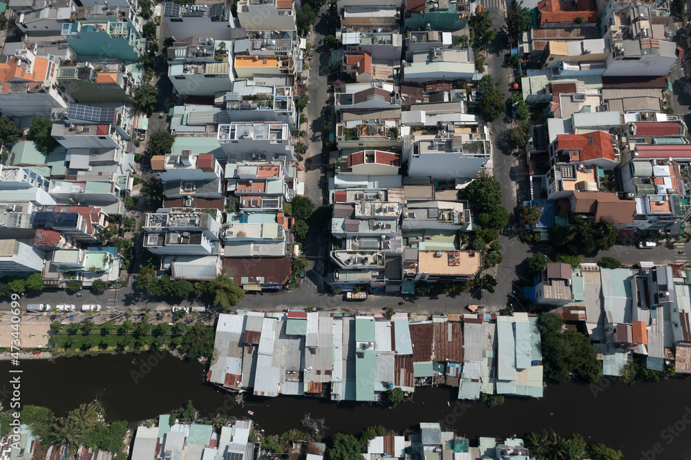 Top down aerial view of residential suburban area featuring rooftops and canal in Ho Chi Minh City, Vietnam on a sunny day.