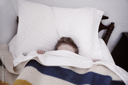 Tablou pe pânză Boy hiding in bed under the covers