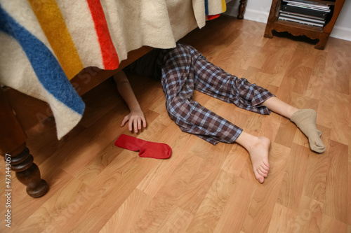 Young boy searching for his lost sock under the bed photo
