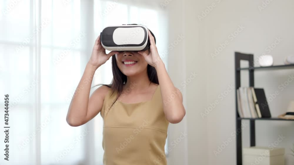 Young asian woman put on vr glasses into virtual simulated world metaverse. Future technology digital cyber universe. Person Enjoying an Experiences of Metaverse Virtual World. Young asian woman put on vr glasses into virtual simulated world metaverse. Future technology digital cyber universe. Person Enjoying an Experiences of Metaverse Virtual World.