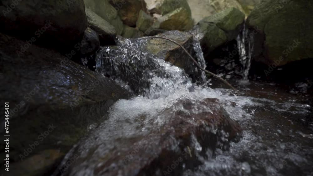 Slow-motion tracking shot of a small stream flowing down rocks Slow-motion tracking shot of a small stream flowing down rocks